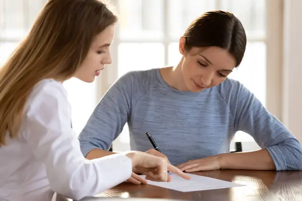 Kvinnelig pasient signerer papirarbeid tett på lege – stockfoto