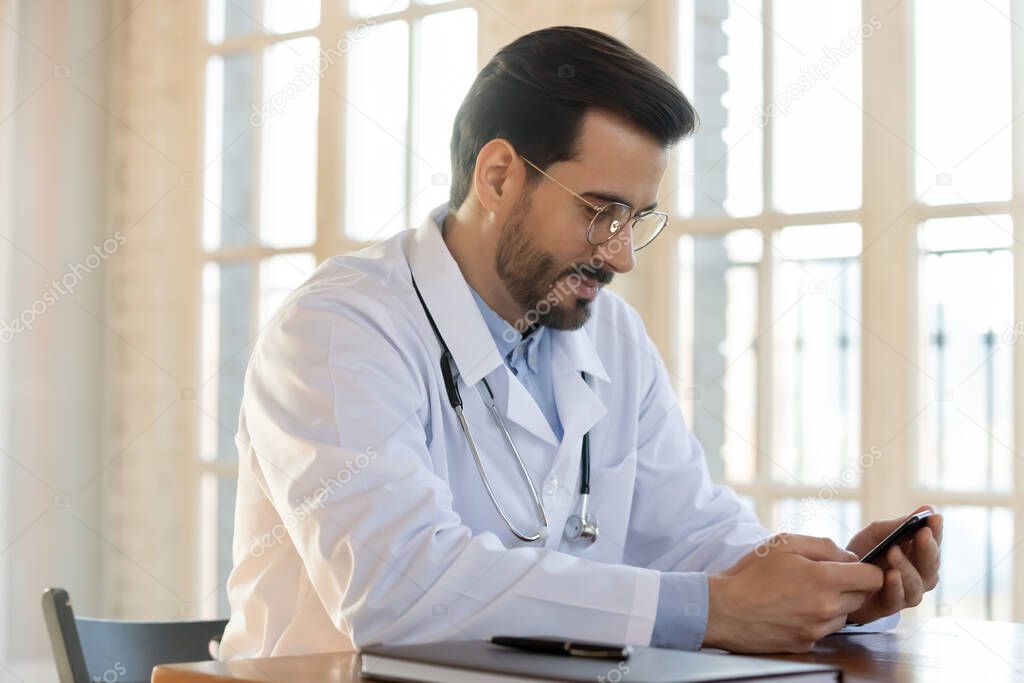 Caucasian male doctor use smartphone at workplace