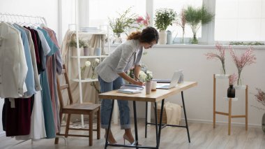 Masanın başında duran konsantre genç bayan dekoratör evrak işlerine odaklanmış.
