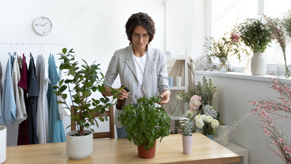 Attentive young female florist enjoying taking care of indoor plants