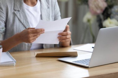 Elinde mektup tutan genç bir kadın bankadan bilgi okuyor.