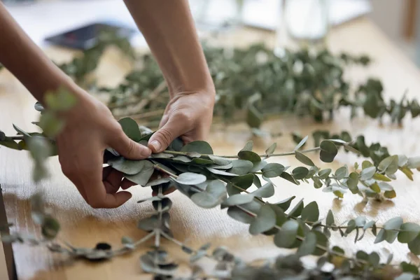 Young woman hands composing branches with leaves to arrange bouquet — Stock Photo, Image