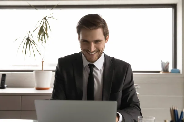 Un uomo d'affari sorridente lavora online sul computer in ufficio — Foto Stock