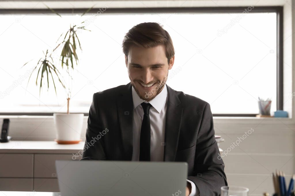 Smiling businessman work online on computer in office