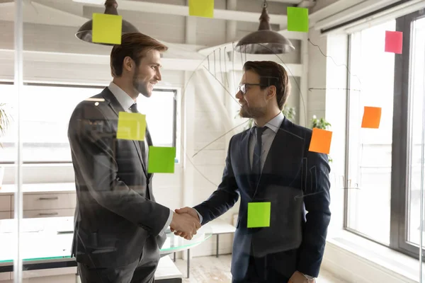 Sonriente apretón de manos de los socios comerciales masculinos después de negociaciones exitosas — Foto de Stock