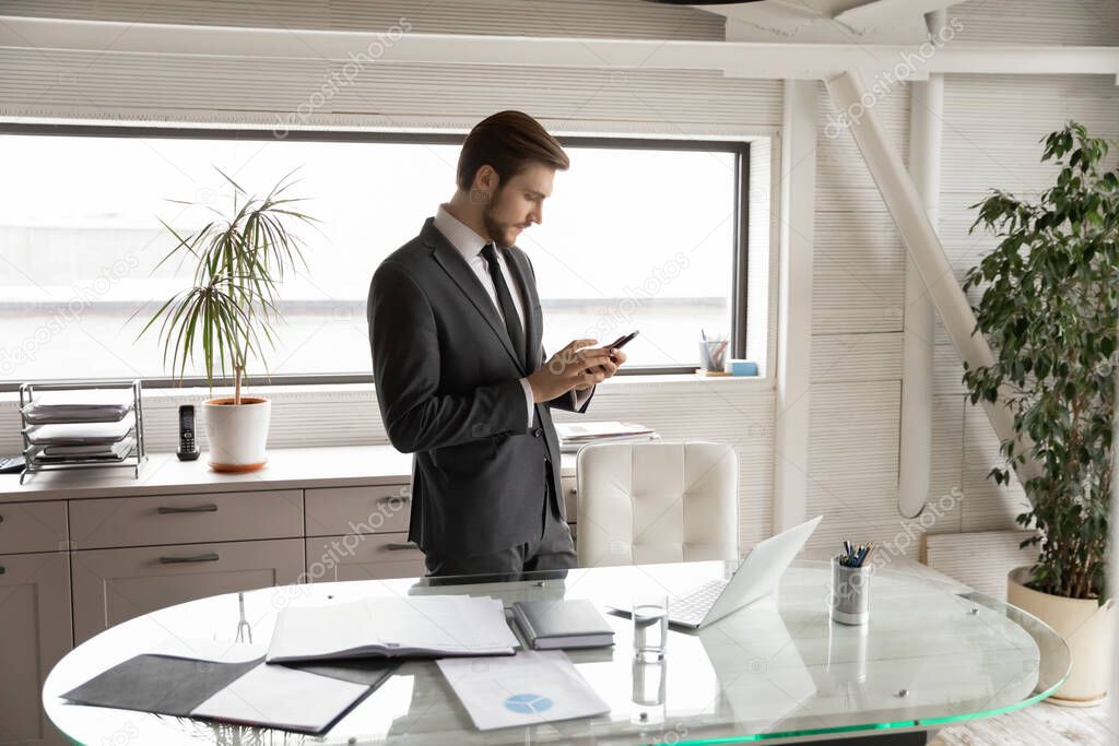 Young Caucasian businessman use modern cellphone in office