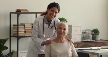 Yaşlı kadın hasta ve tıbbi danışman klinikte poz veriyorlar