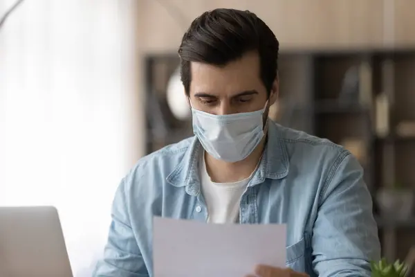 Hombre empleado en facemask trabajo con documentos — Foto de Stock