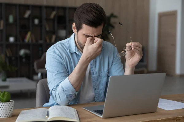 Homem exausto sofre de tontura trabalhando no laptop — Fotografia de Stock