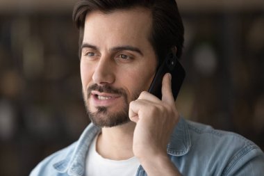 Genç adam modern cep telefonu cihazıyla konuşuyor.