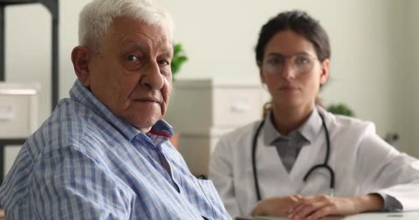 Mayor sonriente clínica paciente masculino y médico de fondo — Vídeos de Stock