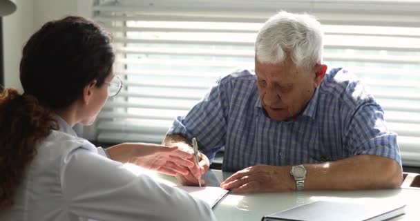 Paciente de edad avanzada firma acuerdo de seguro de salud en clínica — Vídeo de stock