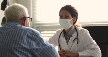 Terapist ziyaretinde yaşlı bir hastayla yüz maskesi takıyor.