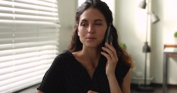 Женщина, держащая смартфон, разговаривает с клиентом, работая на расстоянии. — стоковое видео