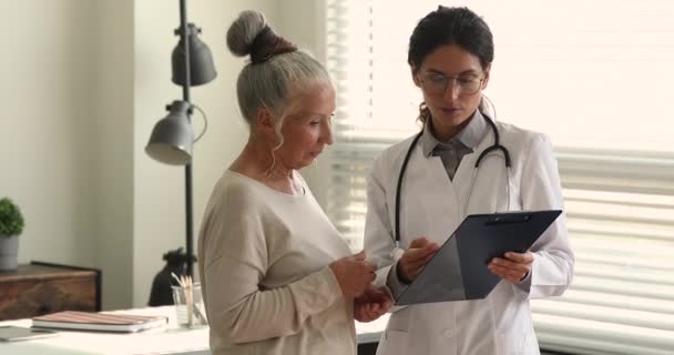 穿制服的年轻医务工作者咨询老年女性病人 — 图库视频影像