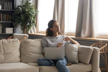 Mutlu kadın kanepede rahatla dizüstü bilgisayarı kullan.