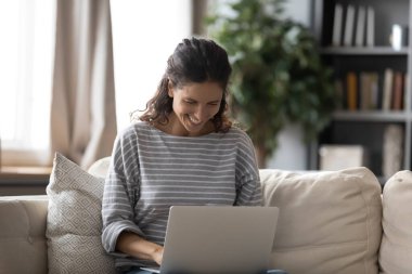 Gülümseyen kadın evde dizüstü bilgisayar kullanarak iyi eğlenceler.