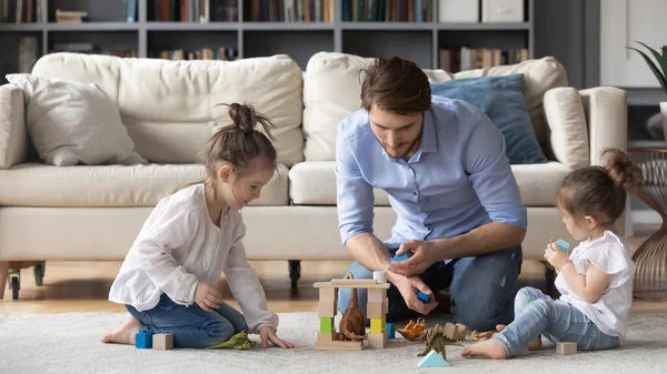 Wide view of caring dad play at home with daughters