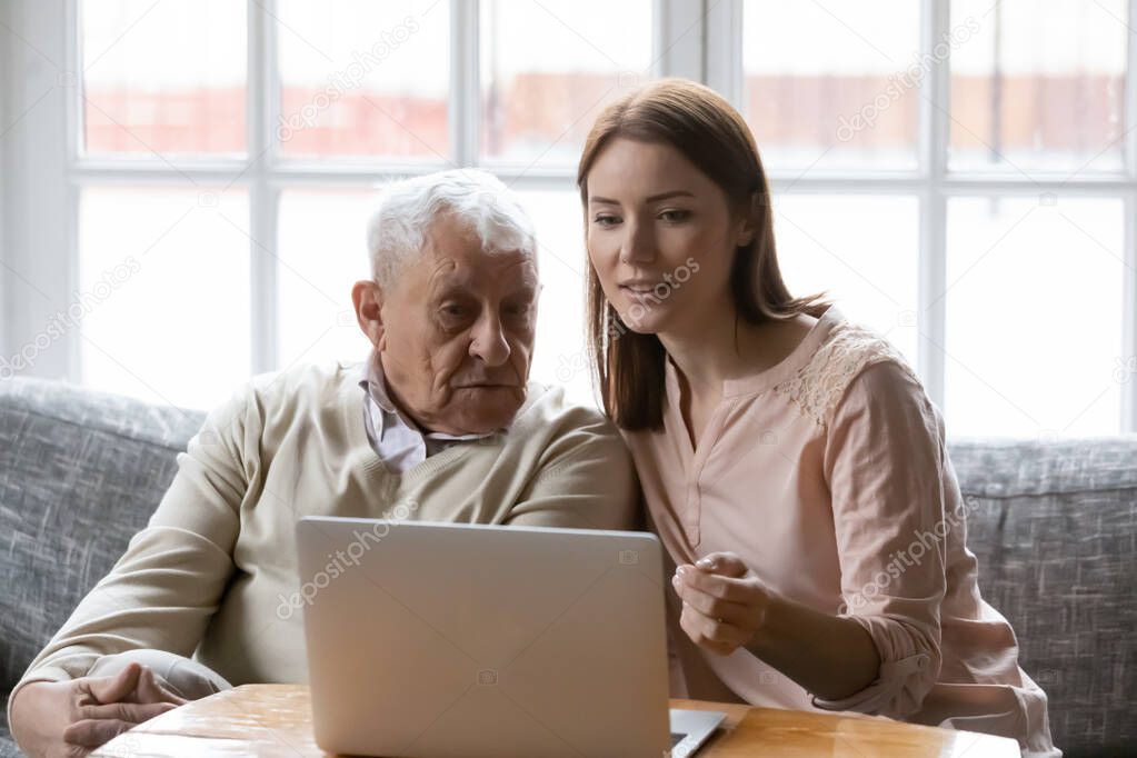 Female volunteer assisting elderly man in shopping online using computer