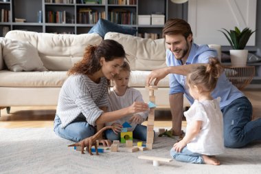 İlgili ebeveynler küçük kızlarıyla tuğlalarla oynarlar.