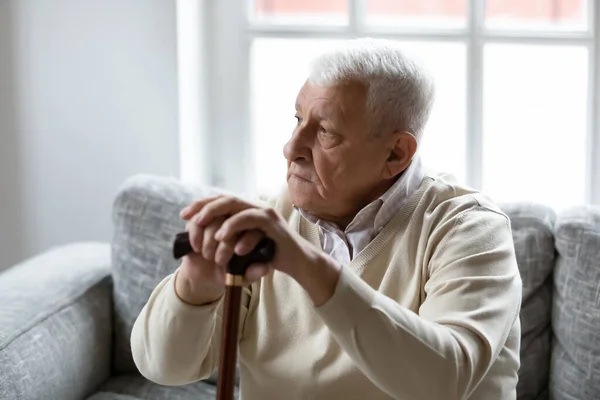 Übermüdeter älterer Mann mit Blindenstock gibt müden Füßen Ruhe — Stockfoto