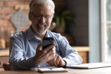 Gözlüklü yaşlı ve yaşlı adam akıllı telefon ekranına bakıyor..