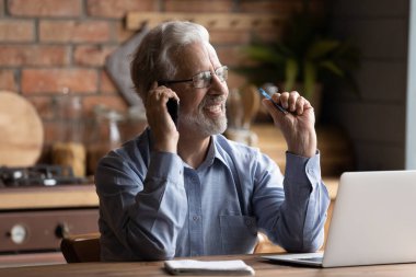 Mutlu orta yaşlı yetişkin iş adamı cep telefonu konuşması yapıyor..