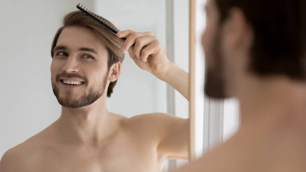 Feliz joven guapo hombre peinado pelo con peine. —  Fotos de Stock