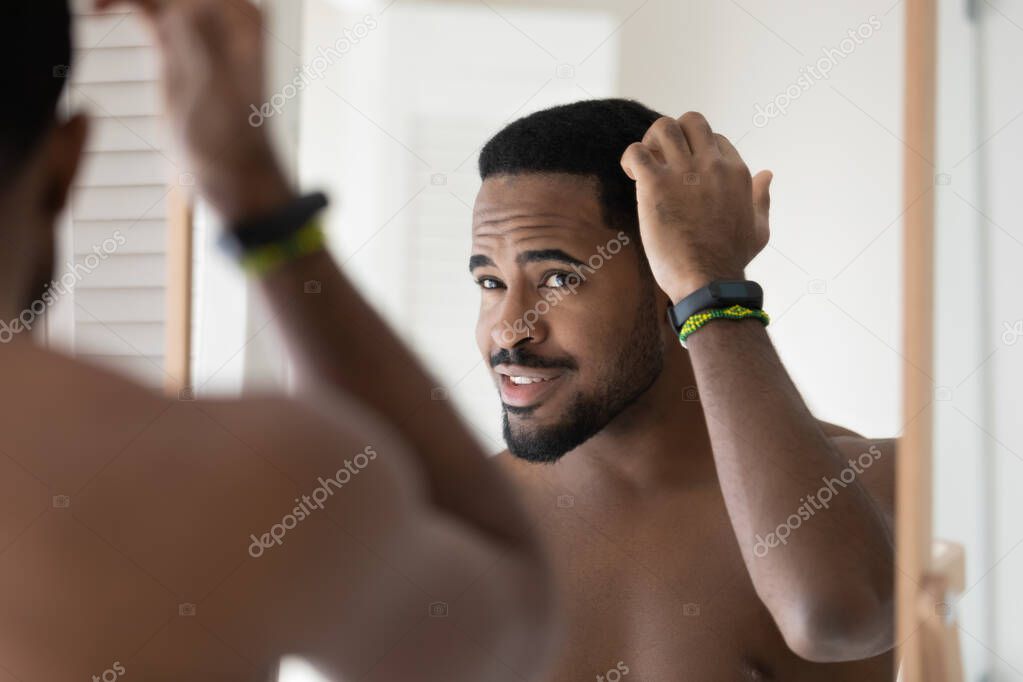 Happy young 30s handsome african american bare man styling hair.