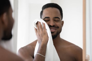 Mutlu genç melez Afrikalı adam havluyla yüzünü siliyor..