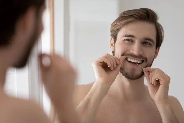 Feliz hombre milenario limpiando dientes con hilo dental. —  Fotos de Stock