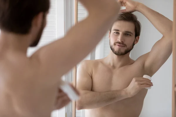 Handsome young 30s shirtless man applying deodorant. — Stock Photo, Image