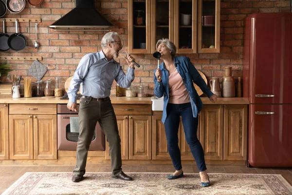 Щасливі старші старші люблячі сімейні пари співають пісні на кухні . — стокове фото