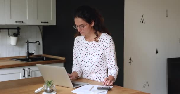 Geconcentreerde jonge vrouw in bril planning maandelijkse budget. — Stockvideo