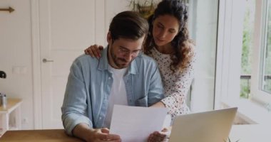 Gülümseyen genç aile çifti gazete mektupları okuyor..