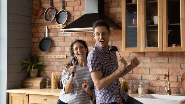 Вдохновленные молодые супруги делают перерыв в приготовлении пищи поют песни — стоковое фото