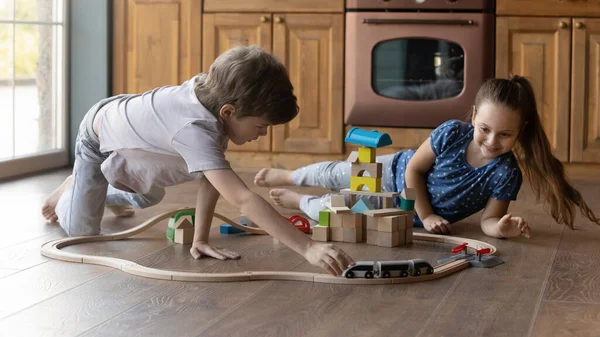 兴奋的妹妹弟弟在温暖的地板上玩玩具火车 — 图库照片