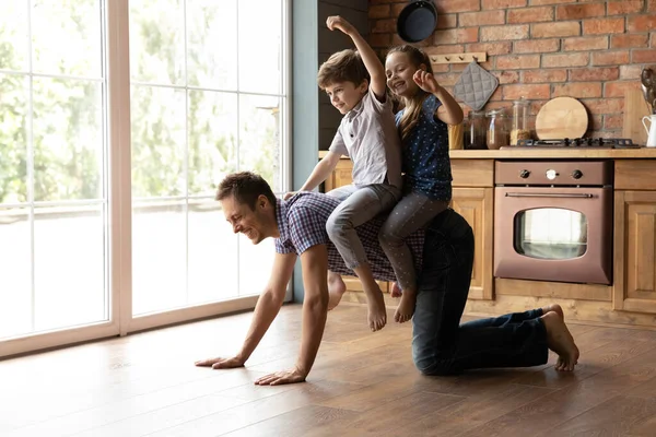 Caring young father giving horseback ride to little daughter son — Stock Photo, Image