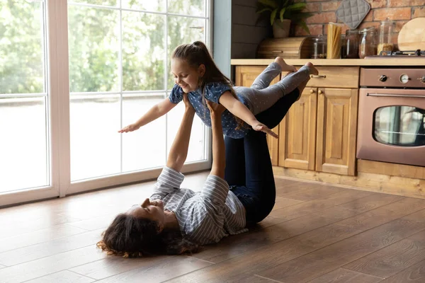 Junge Mutter hebt kleine Tochter beim gemeinsamen Turnen nach oben — Stockfoto