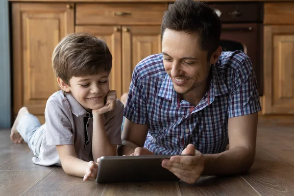 Hermanos mayores y más jóvenes jugando videojuegos en casa usando tableta —  Fotos de Stock