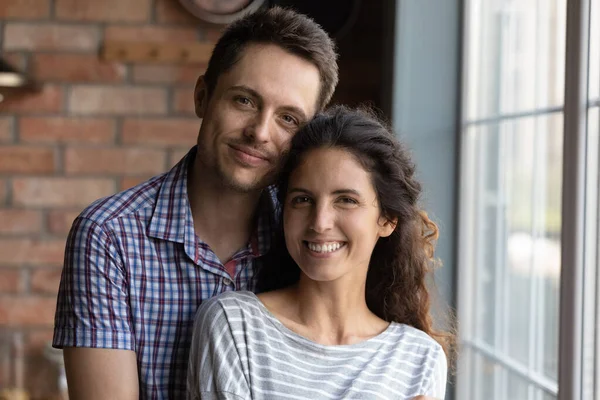 Porträt liebevoller junger Ehepartner, die zu Hause am Fenster stehen — Stockfoto