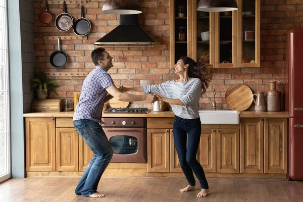 Alegre pareja milenaria bailando en la cocina emocionado con la reubicación — Foto de Stock