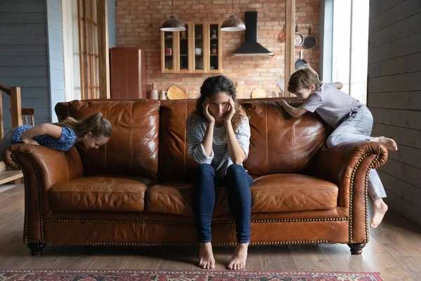 Frustré millénaire nounou étreignant la tête incapable de calmer les enfants hyperactifs — Photo