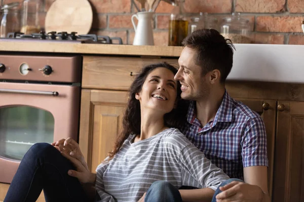 Happy smiling millennial spouses cuddling on kitchen floor celebrating moving — Stock Photo, Image
