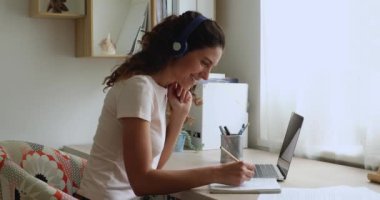 Gülümseyen, kulaklıklı beyaz bir kadın çevrimiçi eğitim sınıfının tadını çıkarıyor..