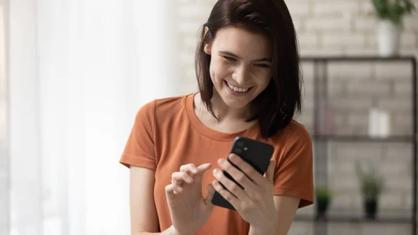 Cheerful millennial woman standing at living room dialing phone number — Stock Photo, Image