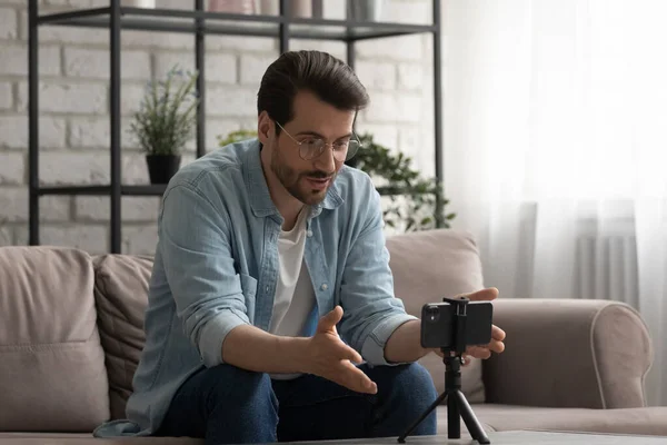 Young man making videocall by cell fixed at holder — Stock Photo, Image