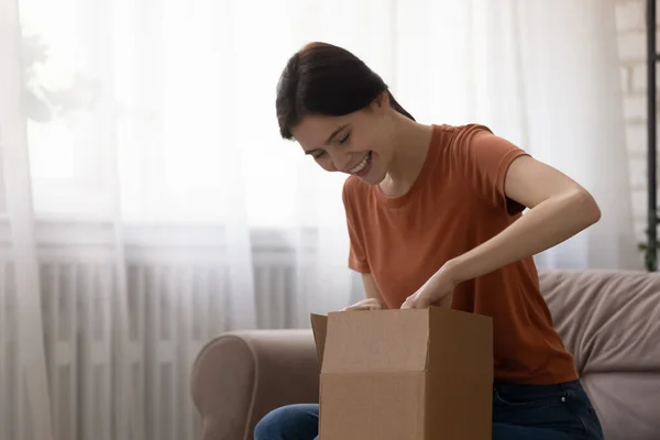 Donna curiosa disimballaggio scatola di cartone ottenere ordine dal negozio online — Foto Stock