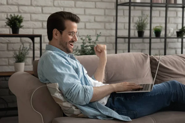 Emocionado joven macho usando portátil gritando sí celebrando buenas noticias — Foto de Stock