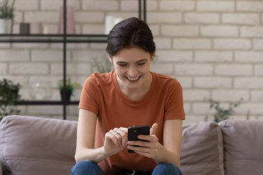 Mutlu genç bayan arkadaşlarıyla telefon ekranında mesajlaşmaya odaklanmış.